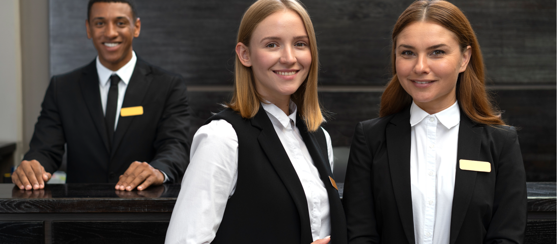 Equipe de hotel reunida, sorrindo e interagindo com entusiasmo, representando um atendimento de excelência e engajamento na hospitalidade.